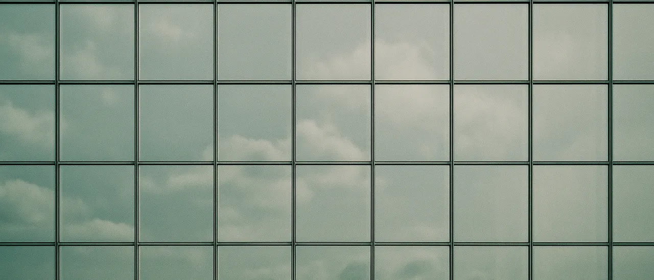 Sauberes Fassadenraster aus Glas und Metall mit Wolkenspiegelungen